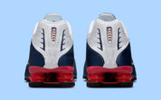 Nike Shox R4 USA 2025 avec tige en cuir synthétique blanc et bleu marine, détails Metallic Silver et Gym Red, amorti Nike Shox à quatre colonnes et semelle extérieure en caoutchouc.