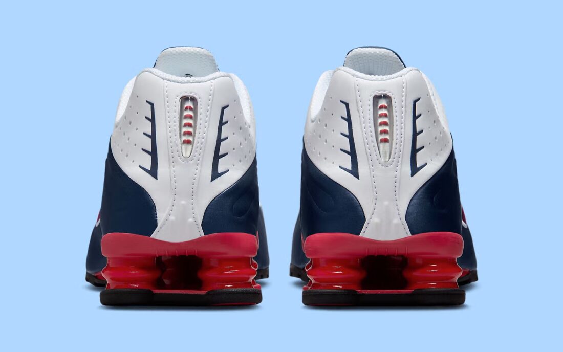 Nike Shox R4 USA 2025 avec tige en cuir synthétique blanc et bleu marine, détails Metallic Silver et Gym Red, amorti Nike Shox à quatre colonnes et semelle extérieure en caoutchouc.
