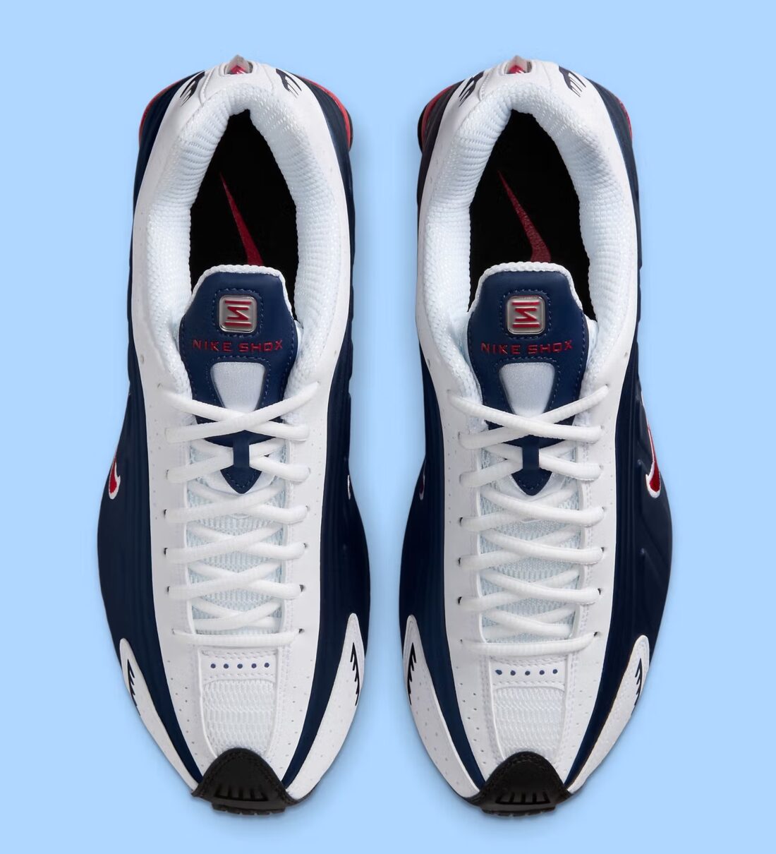 Nike Shox R4 USA 2025 avec tige en cuir synthétique blanc et bleu marine, détails Metallic Silver et Gym Red, amorti Nike Shox à quatre colonnes et semelle extérieure en caoutchouc.
