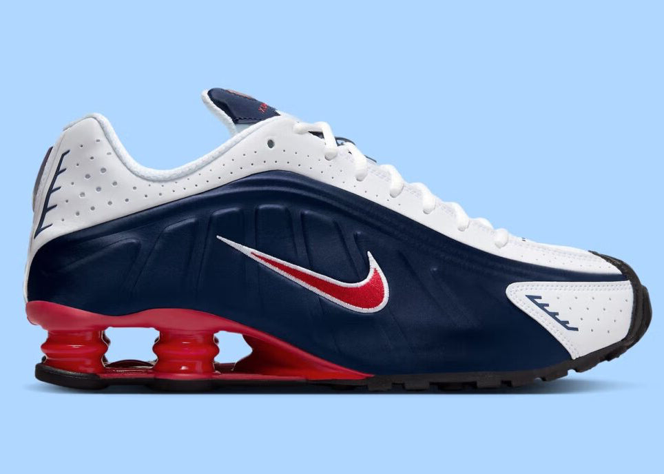 Nike Shox R4 USA 2025 avec tige en cuir synthétique blanc et bleu marine, détails Metallic Silver et Gym Red, amorti Nike Shox à quatre colonnes et semelle extérieure en caoutchouc.