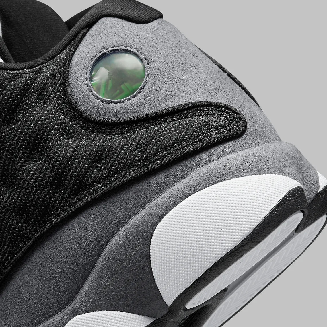 Vue zoomée sur les détails arrières de la Air Jordan 13 Retro Black Flint DJ5982-060 en cuir blanc, suède Flint Grey et mesh noir réfléchissant avec Jumpman rouge.
