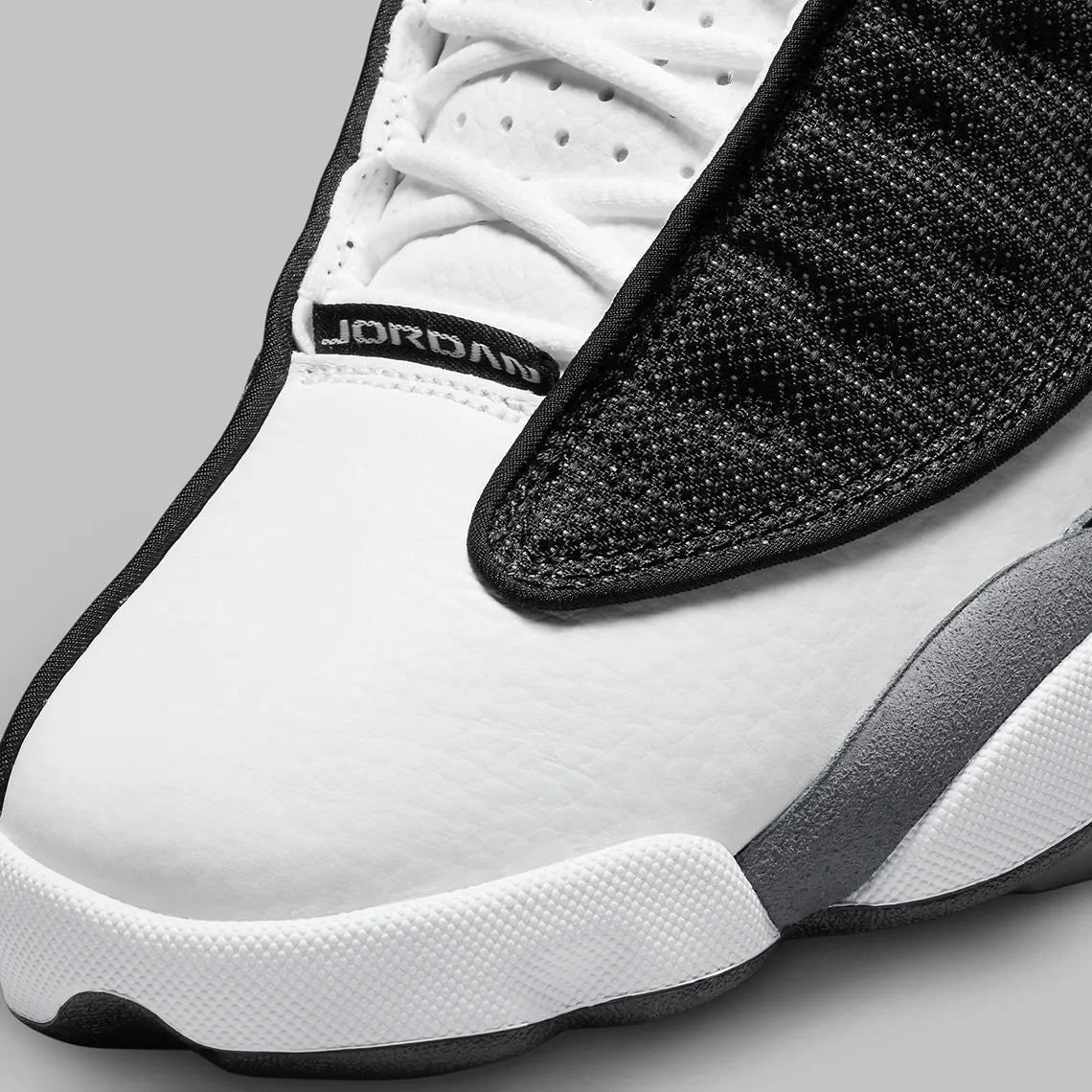 Vue zoomée sur la toe box de la Air Jordan 13 Retro Black Flint DJ5982-060 en cuir blanc, suède Flint Grey et mesh noir réfléchissant avec Jumpman rouge.