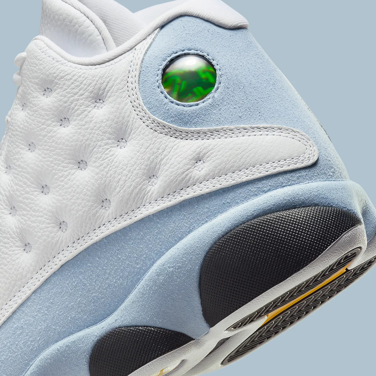 Vue zoomée sur les détails arrières de la Air Jordan 13 Retro Blue Grey 414571-170 en cuir blanc avec panneaux Blue Grey, détails noirs, accents Yellow Ochre et hologramme vert.