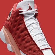 Vue zoomée sur les détails latéraux de la Air Jordan 13 Retro Dune Red DJ5982-601 en textile rouge Dune Red, cuir synthétique blanc, accents Terra Blush et hologramme vert au talon. 
