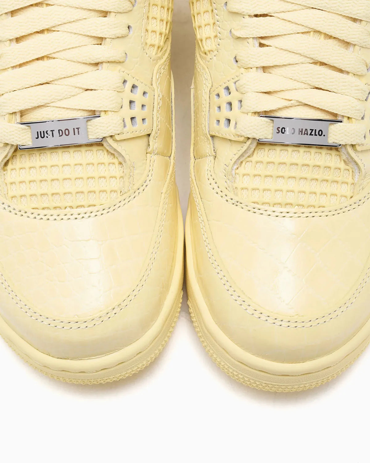 Vue zoomée sur la toe box de la Air Jordan 4 Retro J Balvin Lemonade IW2872-700 en jaune Lemonade avec textures effet crocodile, détails multicolores et smiley J Balvin au talon.