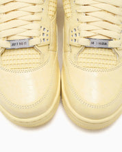 Vue zoomée sur la toe box de la Air Jordan 4 Retro J Balvin Lemonade IW2872-700 en jaune Lemonade avec textures effet crocodile, détails multicolores et smiley J Balvin au talon.