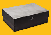 Boite de la sneakers Air Jordan 4 Retro en cuir premium, coloris violet et or Lakers, éléments signature Jumpman et amorti Air visible.