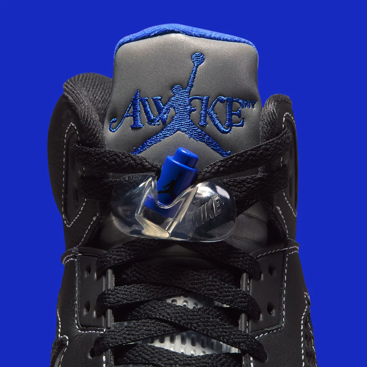 Vue zoomée sur la languette de la Air Jordan 5 Retro Awake NY Black DV4982-004, sneaker noire en cuir avec détails Racer Blue, languette argentée et logos Awake NY.