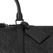 Louis Vuitton Keepall Bandoulière 50 Monogram Shadow Black en cuir de veau Monogram Shadow noir embossé avec poignées roulées, bandoulière amovible, fermeture zippée et finitions métalliques noires.