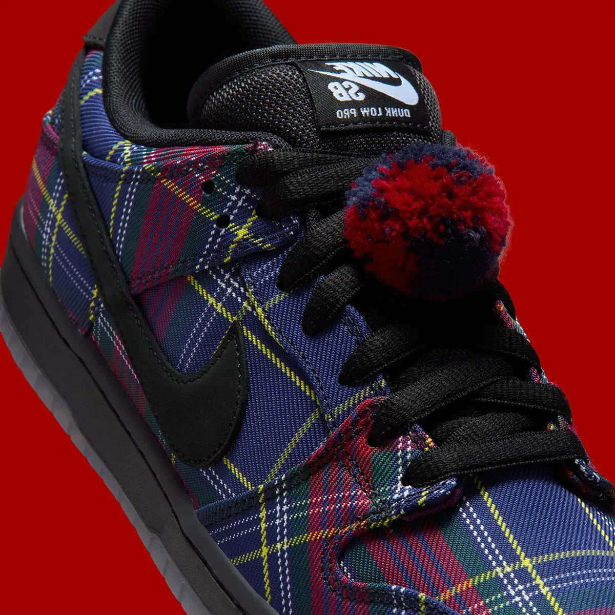 Vue zoomée sur les détails latéraux de la Nike SB Dunk Low Nardwuar avec motif tartan multicolore, cuir premium et semelle skate noire.
