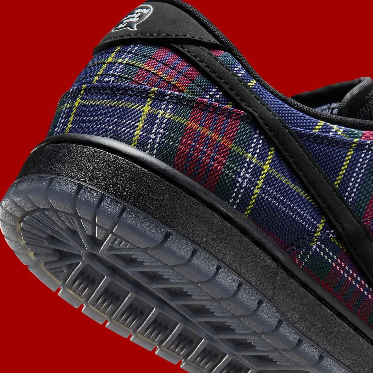 Vue zoomée sur les détails arrières de la Nike SB Dunk Low Nardwuar avec motif tartan multicolore, cuir premium et semelle skate noire.