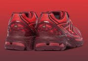 Sneaker New Balance 1906R en mesh gris mercure, cuir synthétique argent, accents rouge crimson, amorti ABZORB et N-ergy, silhouette rétro running premium