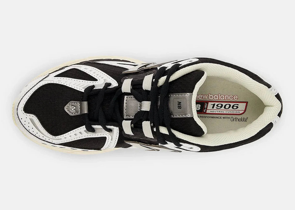 Sneaker New Balance 1906R en mesh blanc, cuir synthétique noir, détails argent métallisé, amorti ABZORB et N-ergy, silhouette rétro running premium