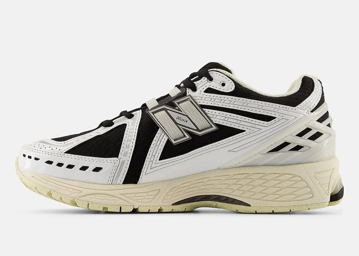 Sneaker New Balance 1906R en mesh blanc, cuir synthétique noir, détails argent métallisé, amorti ABZORB et N-ergy, silhouette rétro running premium