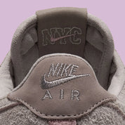 Nike Air Force 1 Low '01 MTA MetroCard en suède gris College Grey avec détails Pink Glaze, hangtag MetroCard et semelle rose translucide.