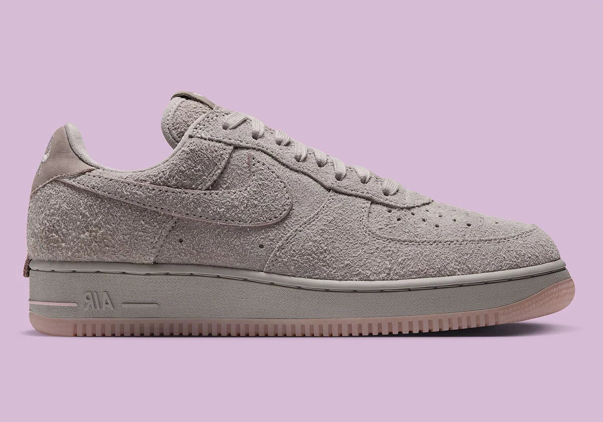 Nike Air Force 1 Low '01 MTA MetroCard en suède gris College Grey avec détails Pink Glaze, hangtag MetroCard et semelle rose translucide.