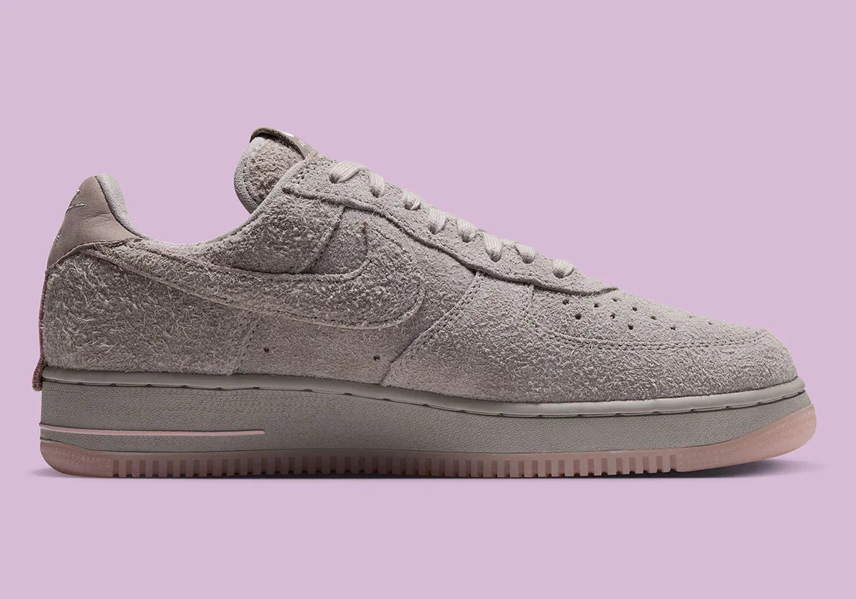 Nike Air Force 1 Low '01 MTA MetroCard en suède gris College Grey avec détails Pink Glaze, hangtag MetroCard et semelle rose translucide.