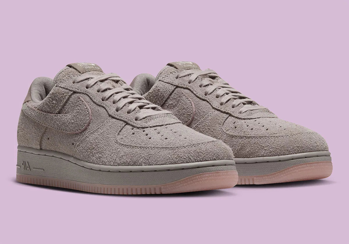 Nike Air Force 1 Low '01 MTA MetroCard en suède gris College Grey avec détails Pink Glaze, hangtag MetroCard et semelle rose translucide.
