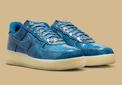 Nike Air Force 1 Low Patent Denim à silhouette basse, avec tige en denim, empiècements vernis contrastés, amorti Nike Air et semelle extérieure en caoutchouc.