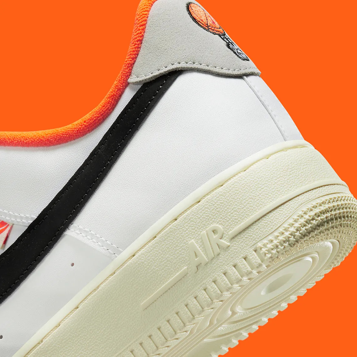 Nike Air Force 1 Low 07 Hoops, sneaker blanche et noire avec détails orange, semelle crème et graphisme basketball au talon vue de profil. 