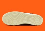 Nike Air Force 1 Low 07 Hoops, sneaker blanche et noire avec détails orange, semelle crème et graphisme basketball au talon vue de profil. 