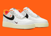 Nike Air Force 1 Low 07 Hoops, sneaker blanche et noire avec détails orange, semelle crème et graphisme basketball au talon vue de profil. 