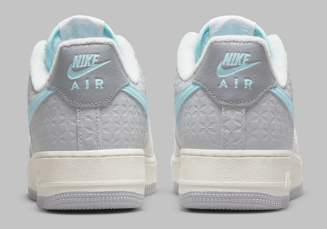 Nike Air Force 1 Low Snowflake DQ0790-001, sneaker Nike Air Force 1 grise en suède avec Swoosh bleu clair et motifs flocons de neige embossés.