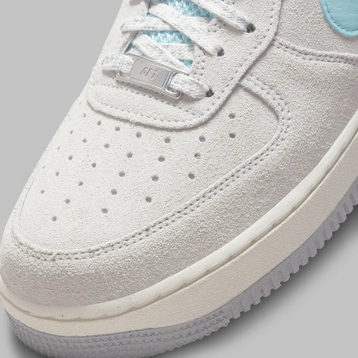 Nike Air Force 1 Low Snowflake DQ0790-001, sneaker Nike Air Force 1 grise en suède avec Swoosh bleu clair et motifs flocons de neige embossés.