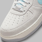 Nike Air Force 1 Low Snowflake DQ0790-001, sneaker Nike Air Force 1 grise en suède avec Swoosh bleu clair et motifs flocons de neige embossés.