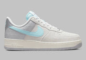 Nike Air Force 1 Low Snowflake DQ0790-001, sneaker Nike Air Force 1 grise en suède avec Swoosh bleu clair et motifs flocons de neige embossés.