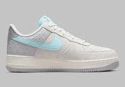 Nike Air Force 1 Low Snowflake DQ0790-001, sneaker Nike Air Force 1 grise en suède avec Swoosh bleu clair et motifs flocons de neige embossés.