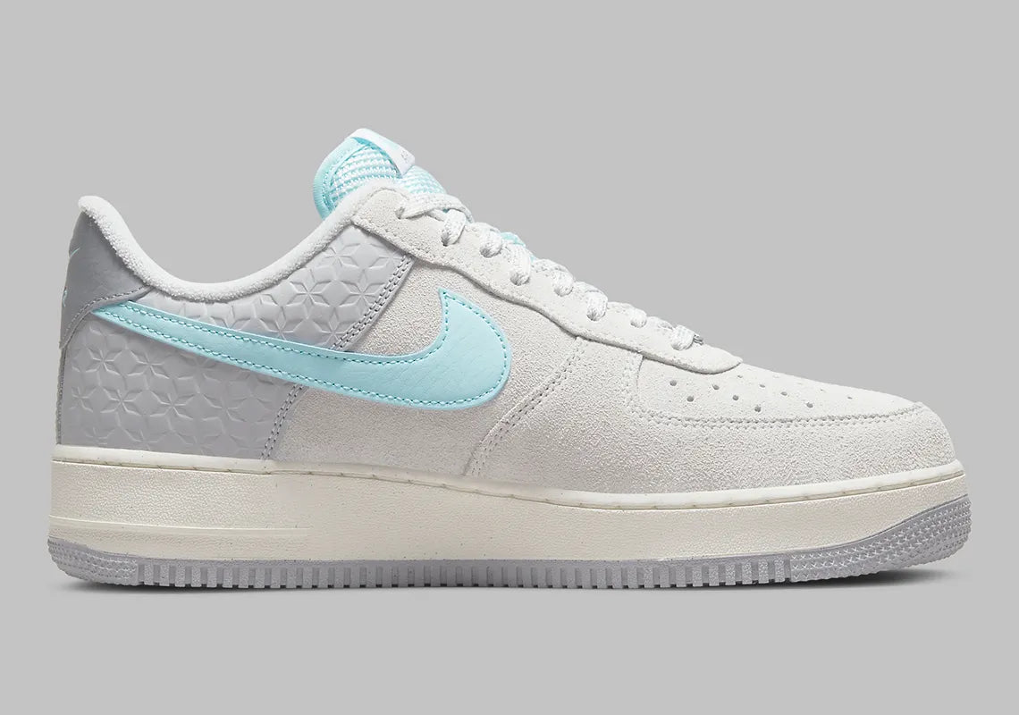 Nike Air Force 1 Low Snowflake DQ0790-001, sneaker Nike Air Force 1 grise en suède avec Swoosh bleu clair et motifs flocons de neige embossés.