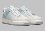 Nike Air Force 1 Low Snowflake DQ0790-001, sneaker Nike Air Force 1 grise en suède avec Swoosh bleu clair et motifs flocons de neige embossés.