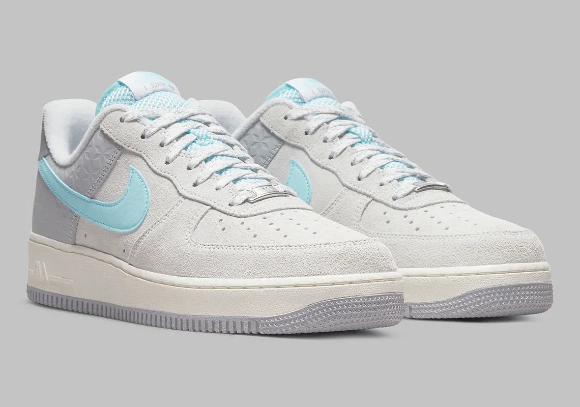 Nike Air Force 1 Low Snowflake DQ0790-001, sneaker Nike Air Force 1 grise en suède avec Swoosh bleu clair et motifs flocons de neige embossés.