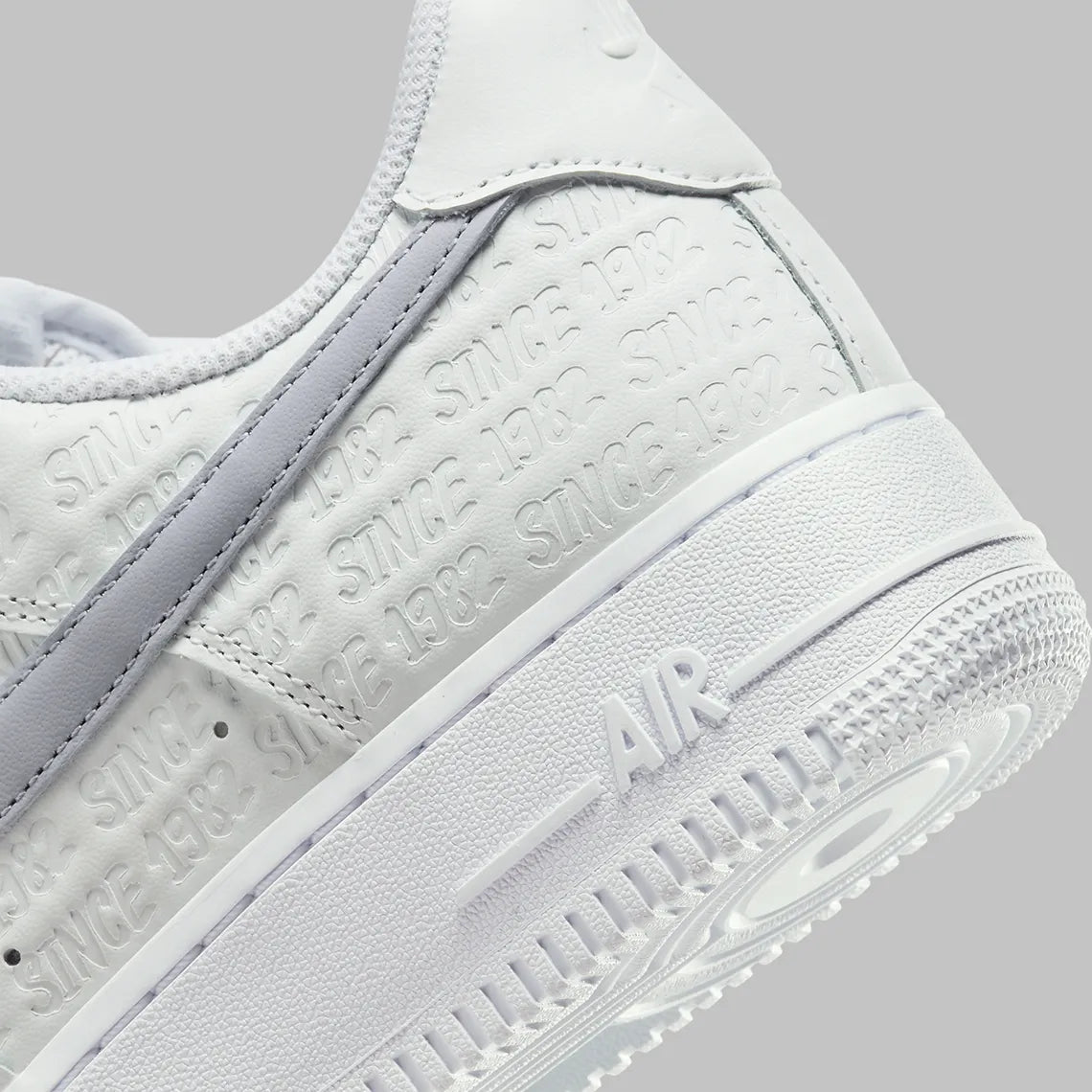 Air Force 1 Low Since 1982, sneaker Nike en cuir Summit White avec Swoosh argenté Metallic Silver et inscriptions Since 1982 en relief vue de profil. 