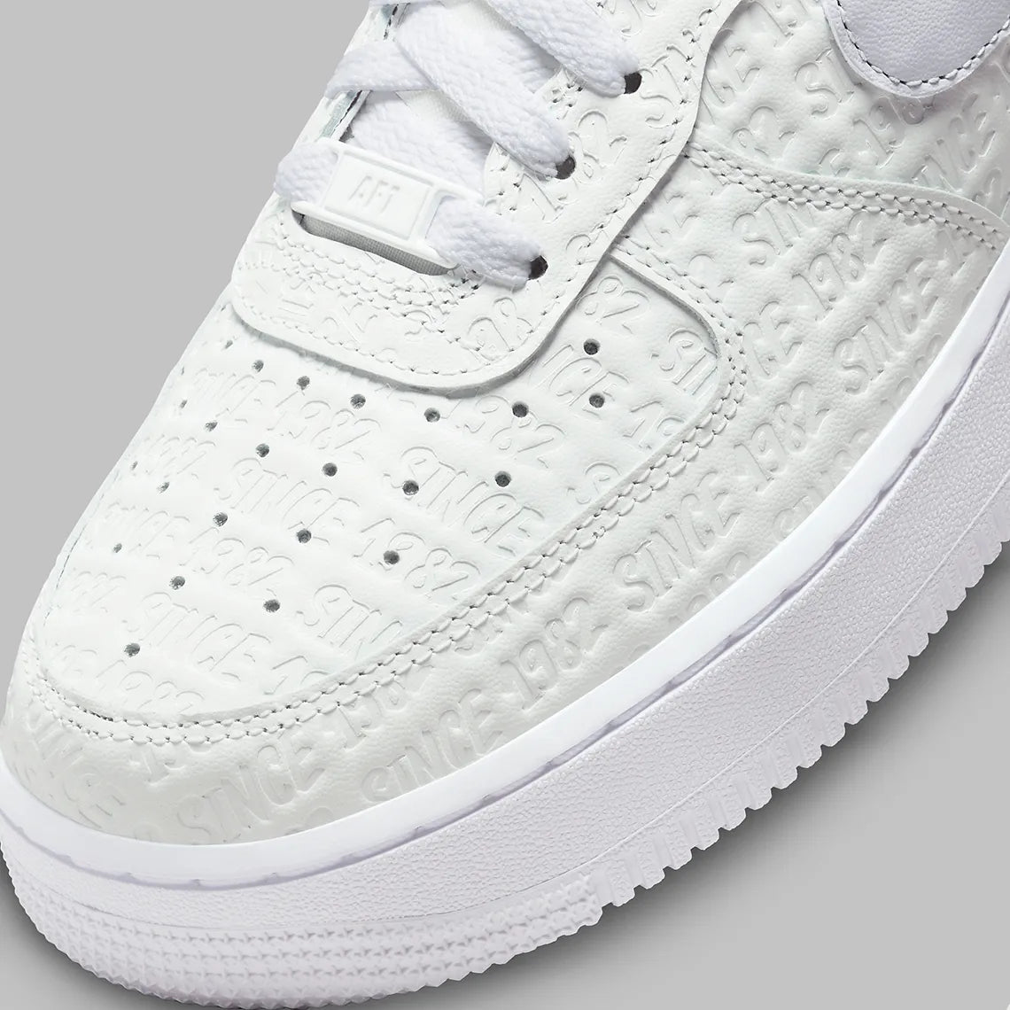 Air Force 1 Low Since 1982, sneaker Nike en cuir Summit White avec Swoosh argenté Metallic Silver et inscriptions Since 1982 en relief vue de profil. 