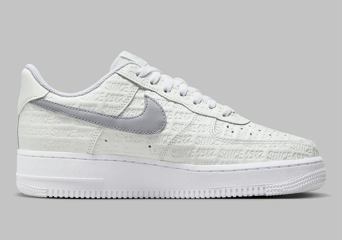 Air Force 1 Low Since 1982, sneaker Nike en cuir Summit White avec Swoosh argenté Metallic Silver et inscriptions Since 1982 en relief vue de profil. 