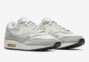 Nike Air Max 1 Vast Grey grise avec empiècements en suède et cuir, touches Spruce Aura et Ridgerock et unité Air visible vue de 3/4 face. 