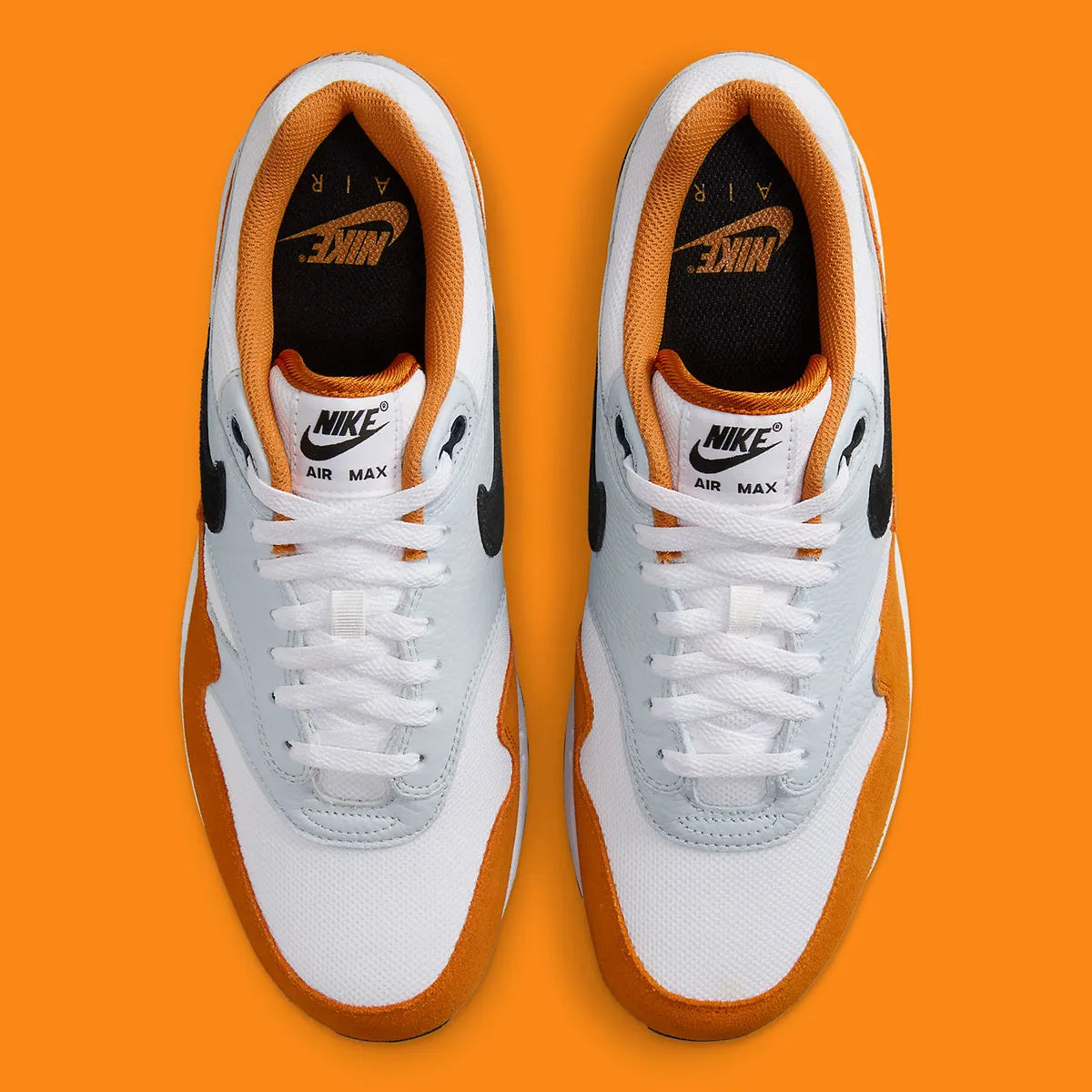 Nike Air Max 1 Monarch FN6952-101 en mesh blanc, cuir gris et suède orange Monarch avec Swoosh noir et unité Air visible.