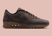 Nike Air Max 90 Shadow Brown, sneaker Nike marron avec empeigne multi-matières, Swoosh latéral et unité Air visible au talon.