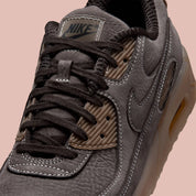 Nike Air Max 90 Shadow Brown, sneaker Nike marron avec empeigne multi-matières, Swoosh latéral et unité Air visible au talon.
