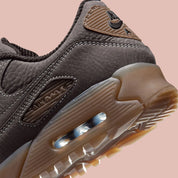 Nike Air Max 90 Shadow Brown, sneaker Nike marron avec empeigne multi-matières, Swoosh latéral et unité Air visible au talon.