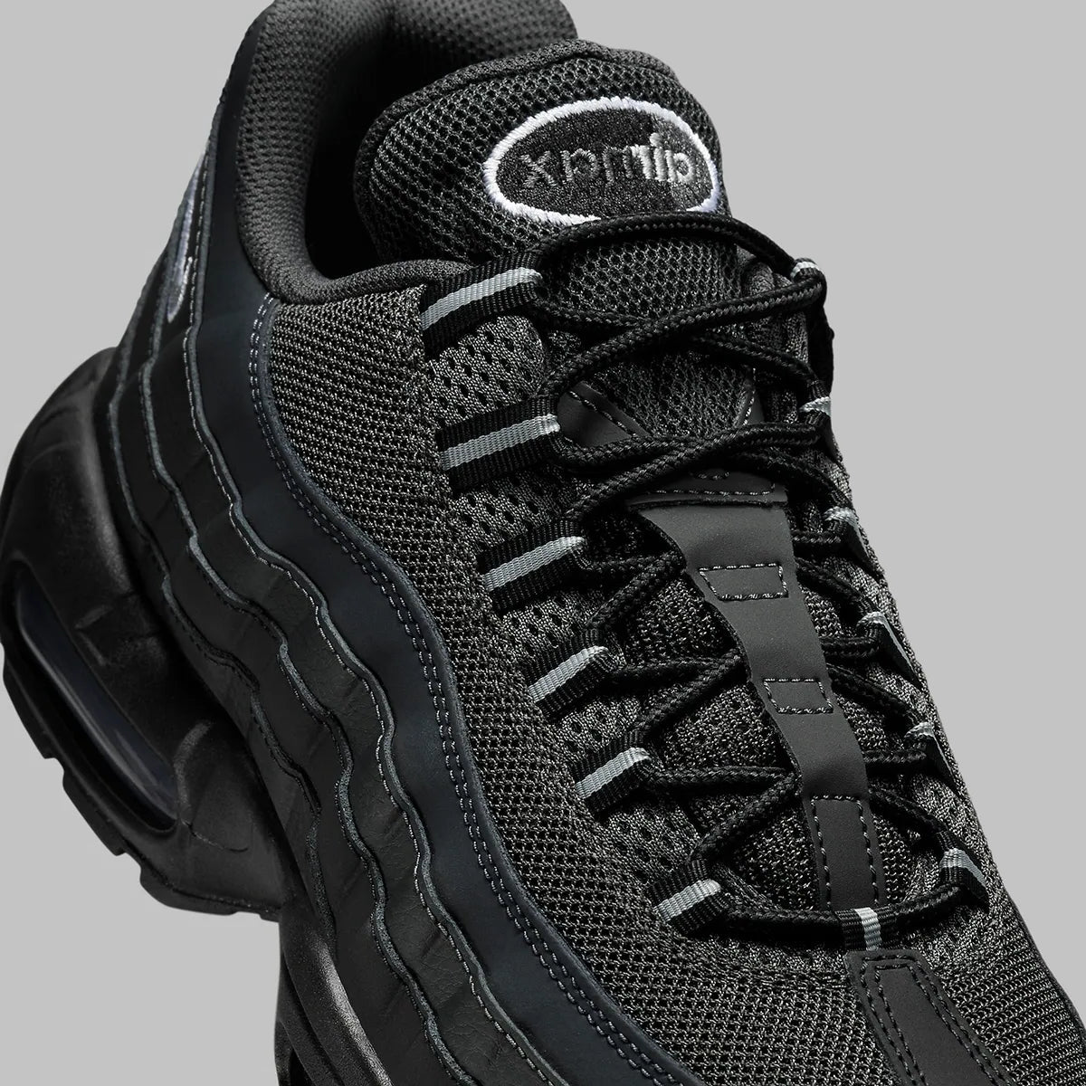 Vue zoomée sur les détails latéraux de la Nike Air Max 95 Black Silver noire et grise avec panneaux superposés Black, Anthracite et Stadium Grey et unités Nike Air visibles.