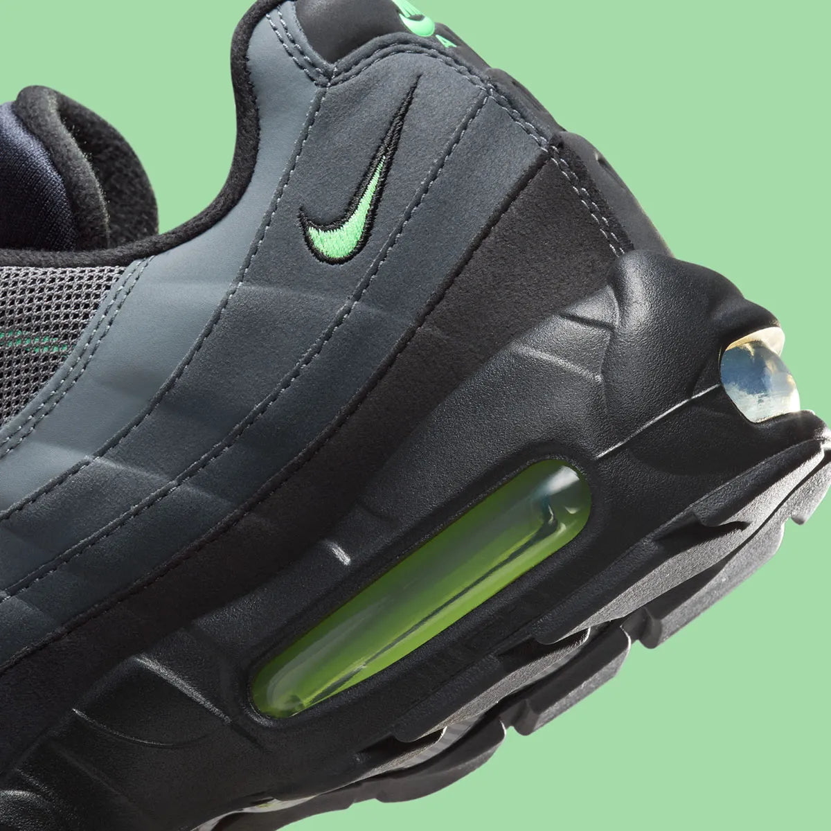 Nike Air Max 95 Vapor Green noire et grise avec panneaux superposés, détails vert Vapor Green et unités Nike Air visibles.