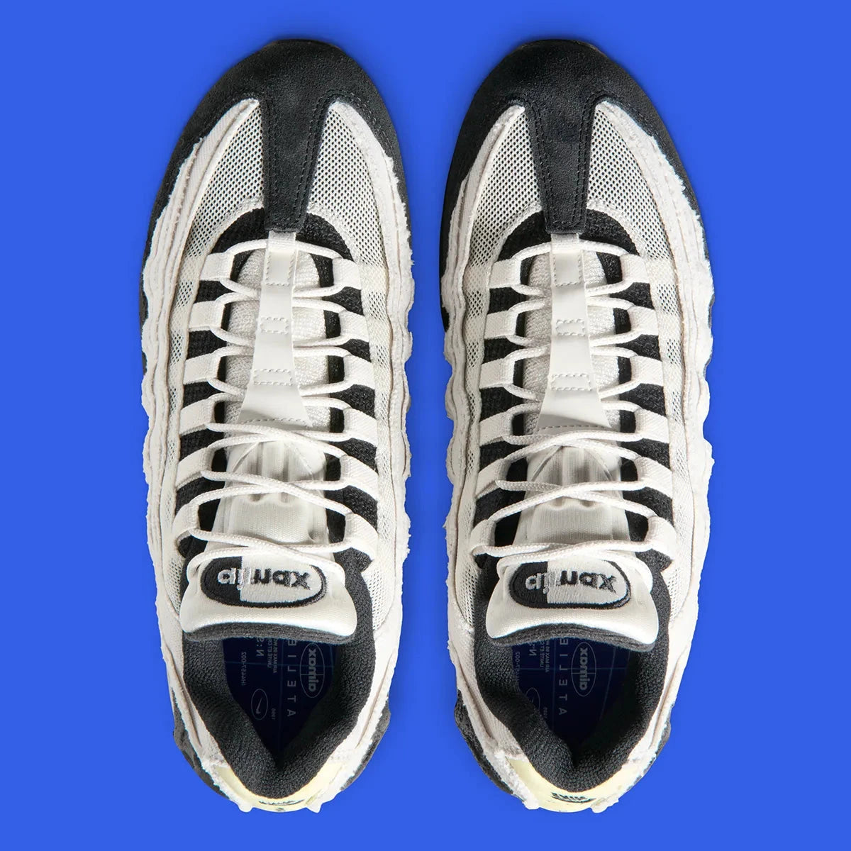 Nike Air Max 95 Big Bubble City Pack Paris Atelier, sneaker en toile claire à bords bruts avec détails Racer Blue et unités Max Air visibles.