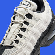Nike Air Max 95 Big Bubble City Pack Paris Atelier, sneaker en toile claire à bords bruts avec détails Racer Blue et unités Max Air visibles.