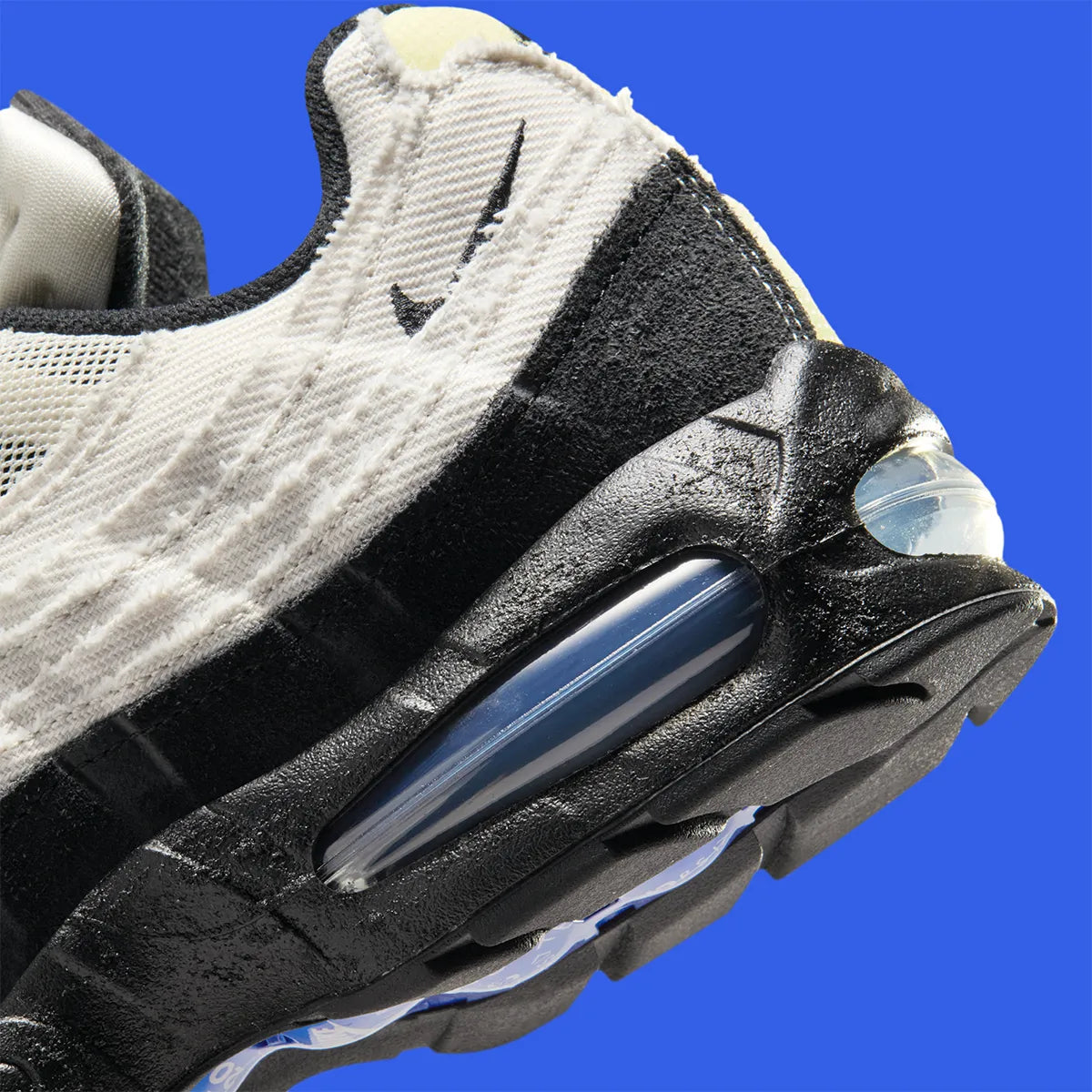 Nike Air Max 95 Big Bubble City Pack Paris Atelier, sneaker en toile claire à bords bruts avec détails Racer Blue et unités Max Air visibles.