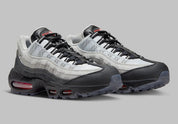 Nike Air Max 95 Fish Scales grise, noire et blanche avec motif écailles au talon, empiècements texturés et unités Air visibles.