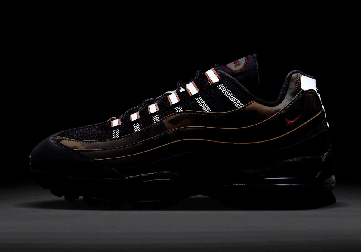 Sneakers Nike Air Max 95 Safety Orange Camo en matériaux premium avec motif camouflage, accents orange et unités Air visibles vue de nuit pour faire ressortir le côté réfléchissant de la paire. 
