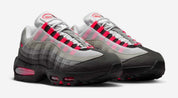 Nike Air Max 95 OG Big Bubble Reverse Solar Red avec tige en mesh, cuir synthétique et suède en dégradé de gris, accents Solar Red, unités Big Bubble Air visibles et semelle extérieure en caoutchouc vue de 3/4 face. 